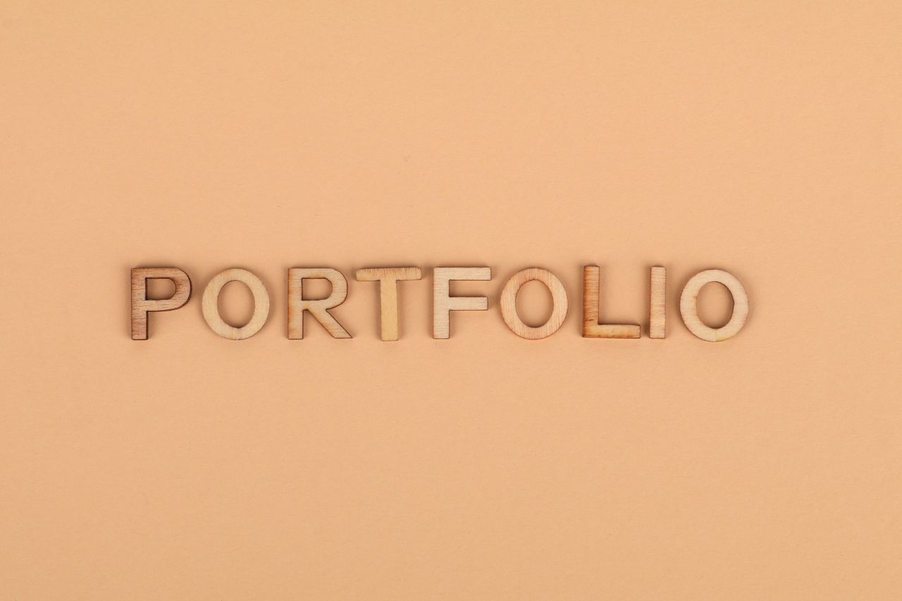Close-up of wooden letters spelling 'PORTFOLIO' on a yellow background, offering creative copyspace.